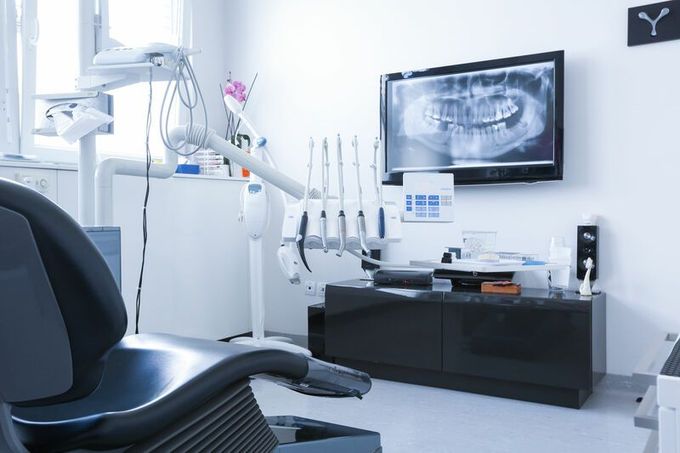 Un consultorio dental con un sillón dental y un televisor en la pared.