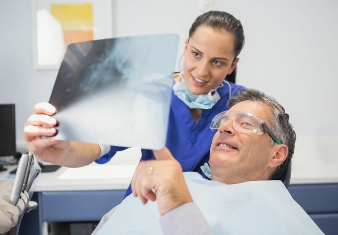 Un dentista está mirando una radiografía de los dientes de un paciente.