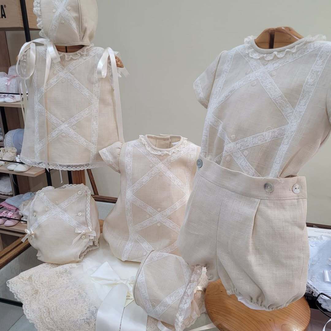 Se exhiben varios conjuntos de bebé de color marrón, incluidos vestidos, camisas, pantalones bombachos y gorros.