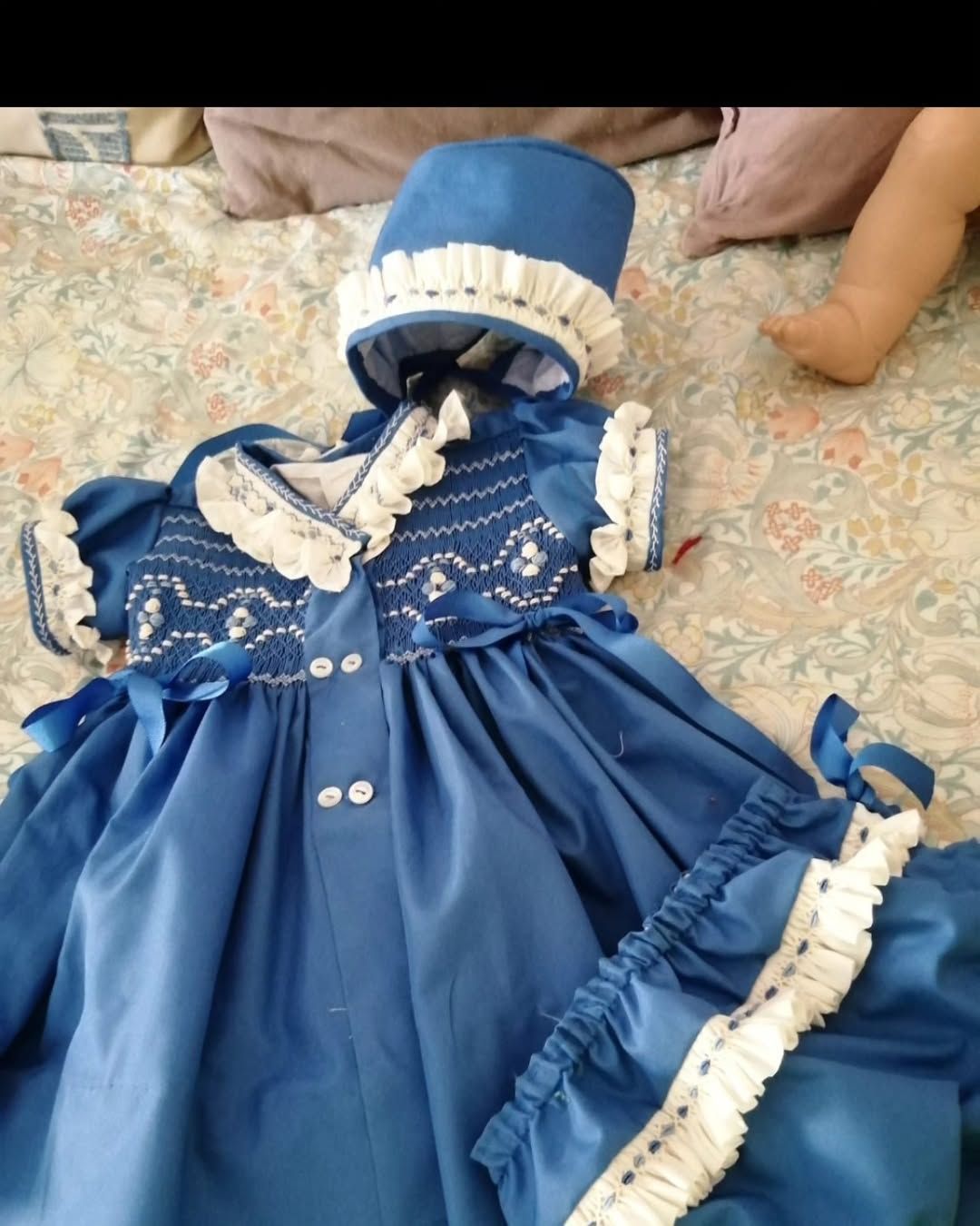 Conjunto de bebé azul con gorrito y cubrepañal; ribete de encaje blanco y detalle de fruncido.