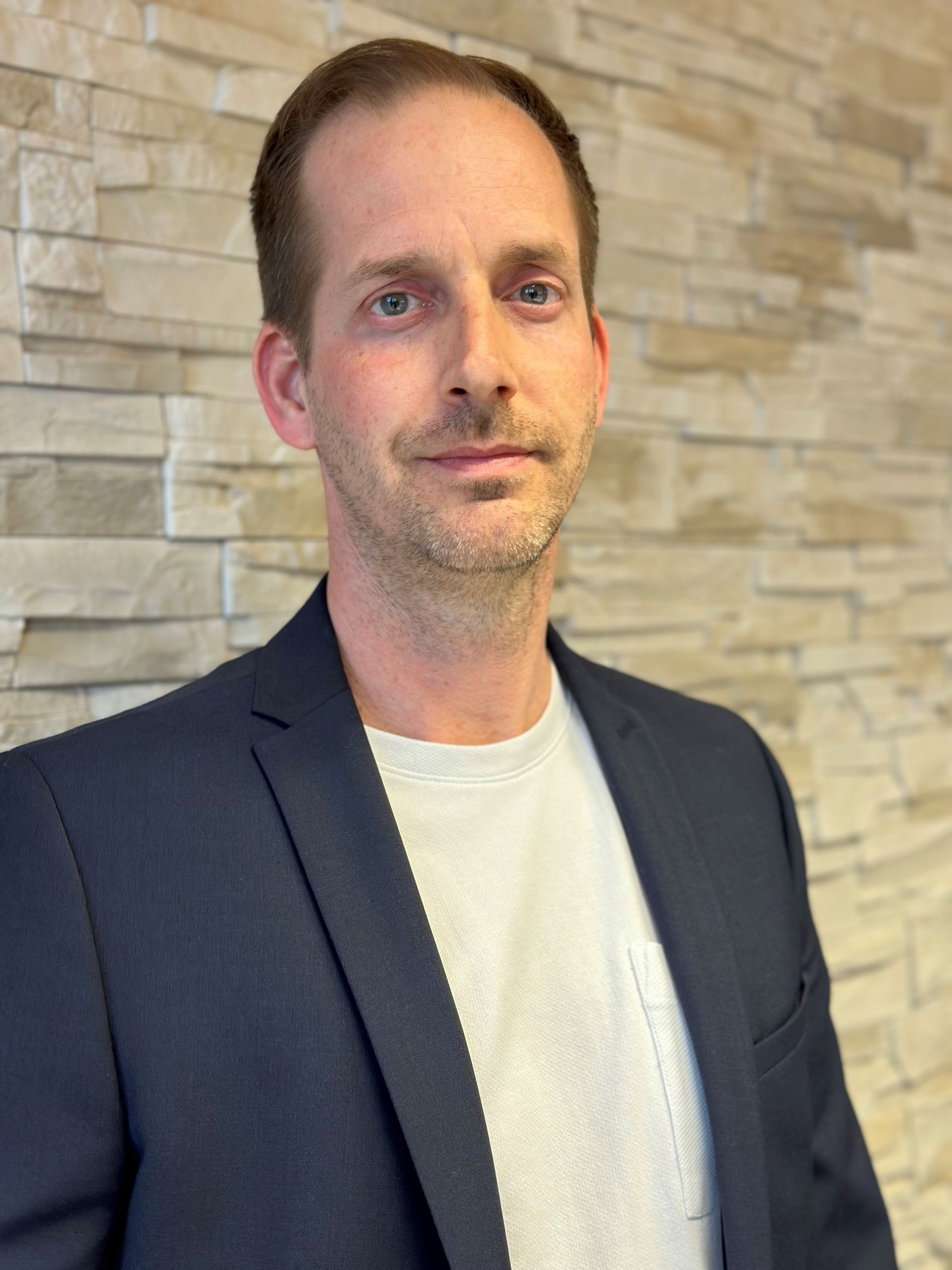 Anordnung von sieben leuchtend bunten, zylindrischen Objekten: Grün, Gelb, Orange, Rot, Dunkelblau, Weiß, Bronze und Silber.