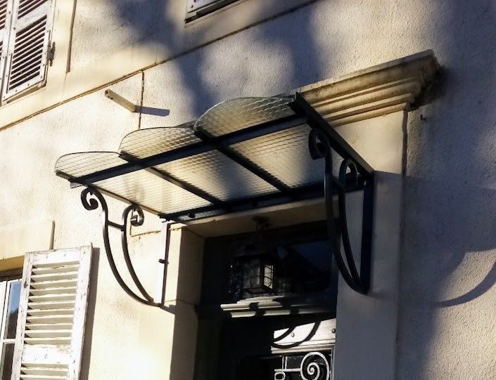 Une marquise fabriquée et posée devant une porte d'entrée
