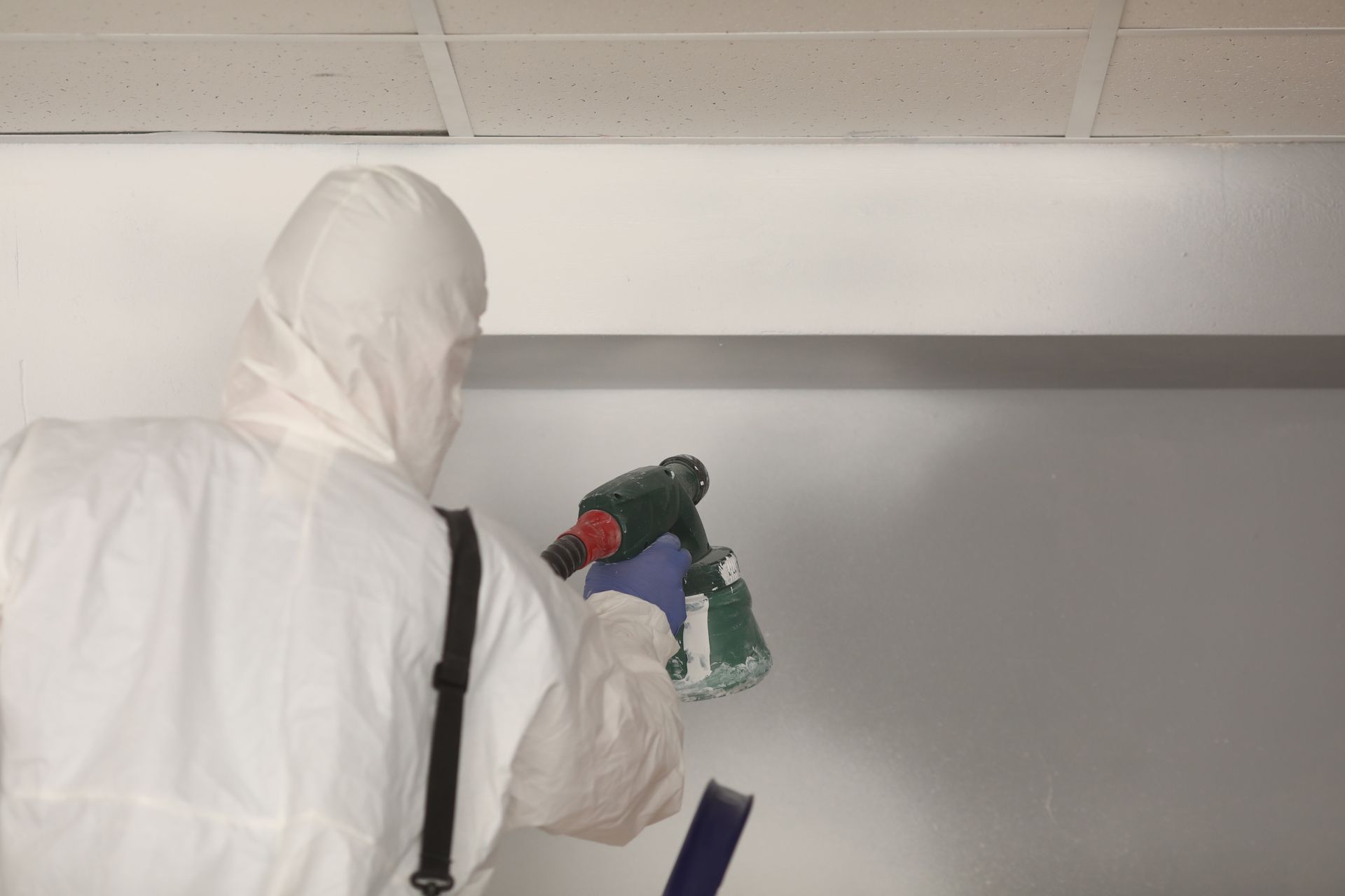 Un artisan en train de peindre un mur au pistolet