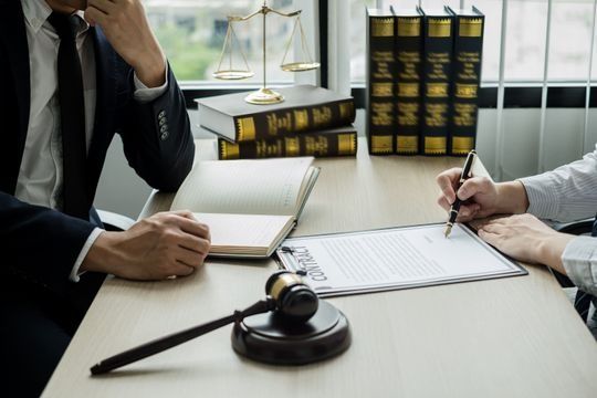 Dos hombres están sentados en una mesa con un mazo y un portapapeles.