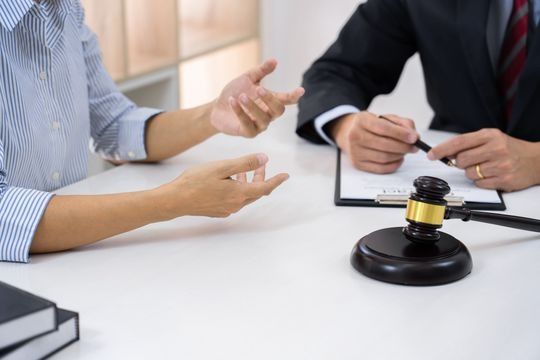 Un hombre y una mujer están sentados en una mesa con un mazo de juez.