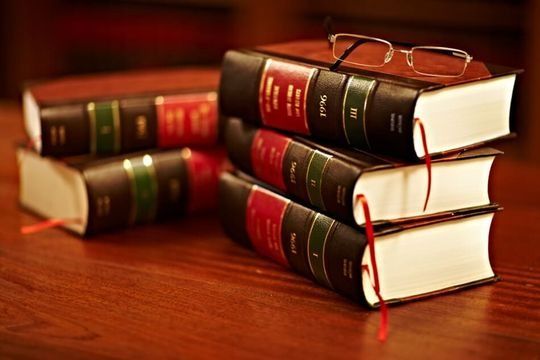 Una pila de libros con vasos encima de ellos sobre una mesa de madera.