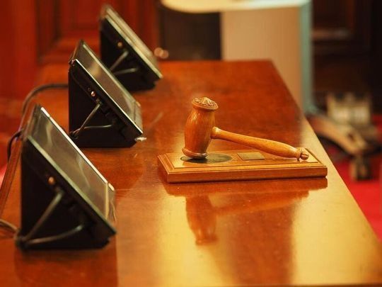 Un mazo de juez de madera está sobre una mesa de madera al lado de una fila de micrófonos.