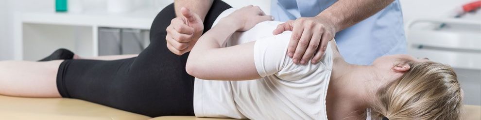 Eine Frau liegt auf einem Tisch und bekommt von einem Arzt eine Massage.