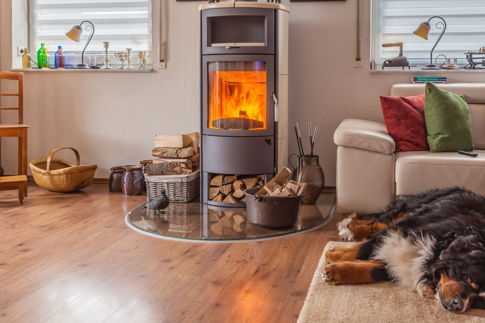 Un salon chaleureux avec une cheminée, un chien endormi sur un tapis, un parquet et un canapé orné de coussins colorés.