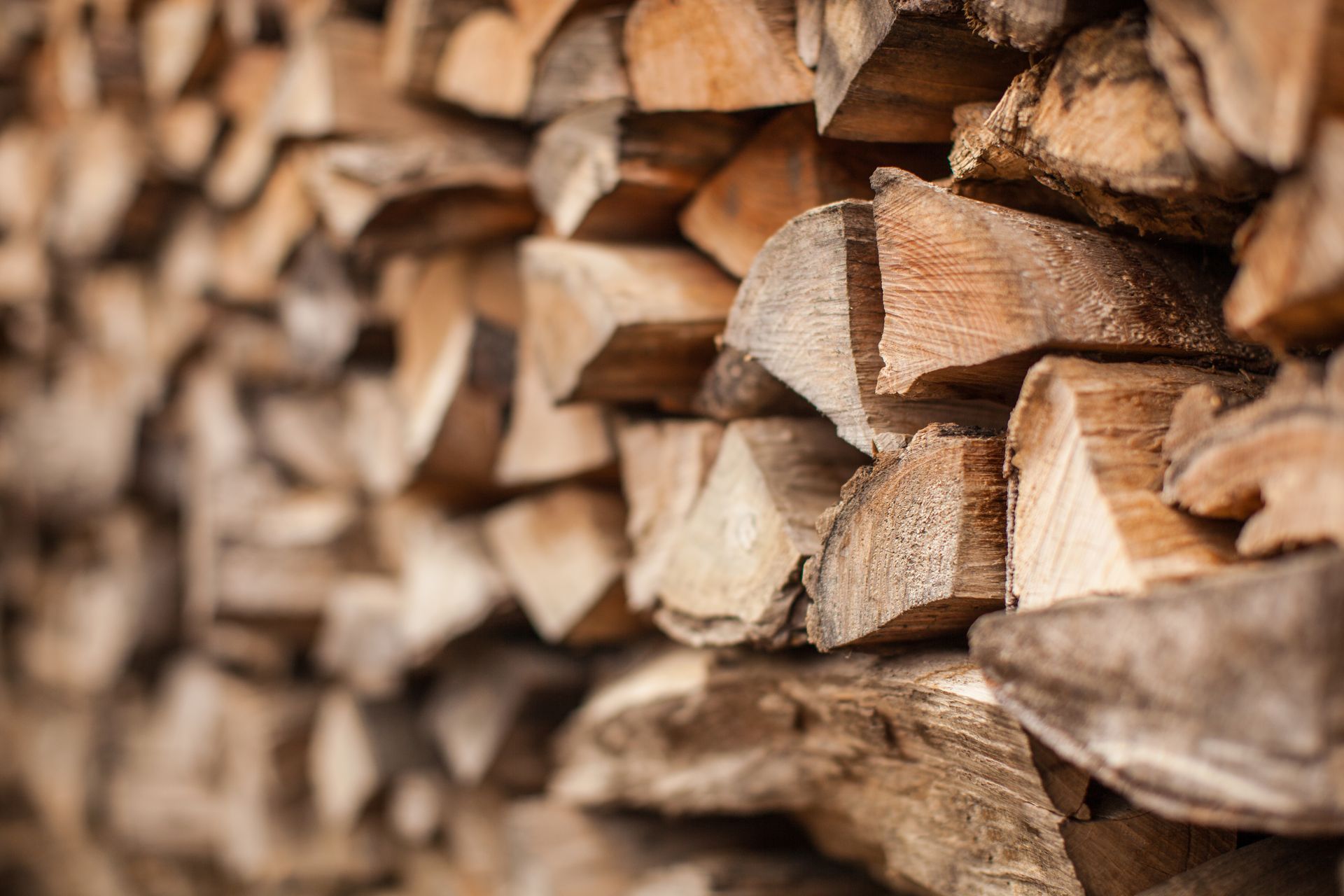Gros plan en biais d'une pile de bûches fendues soigneusement empilées, mettant en valeur les différentes textures et les tons chauds du bois.