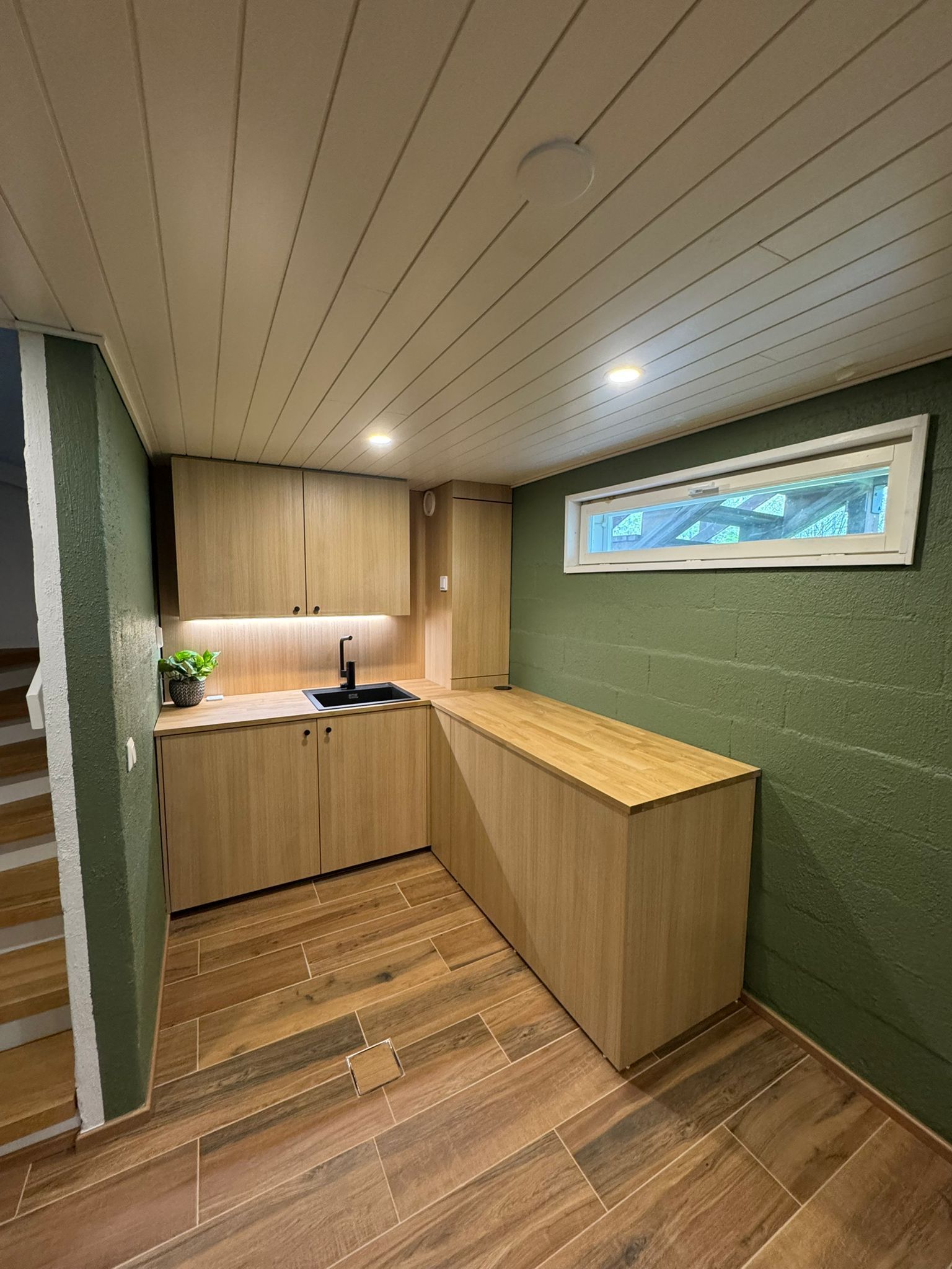 Huoneistoremontti keittiöasennus puunväriset kaapit ja vihreä seinä Renomen.