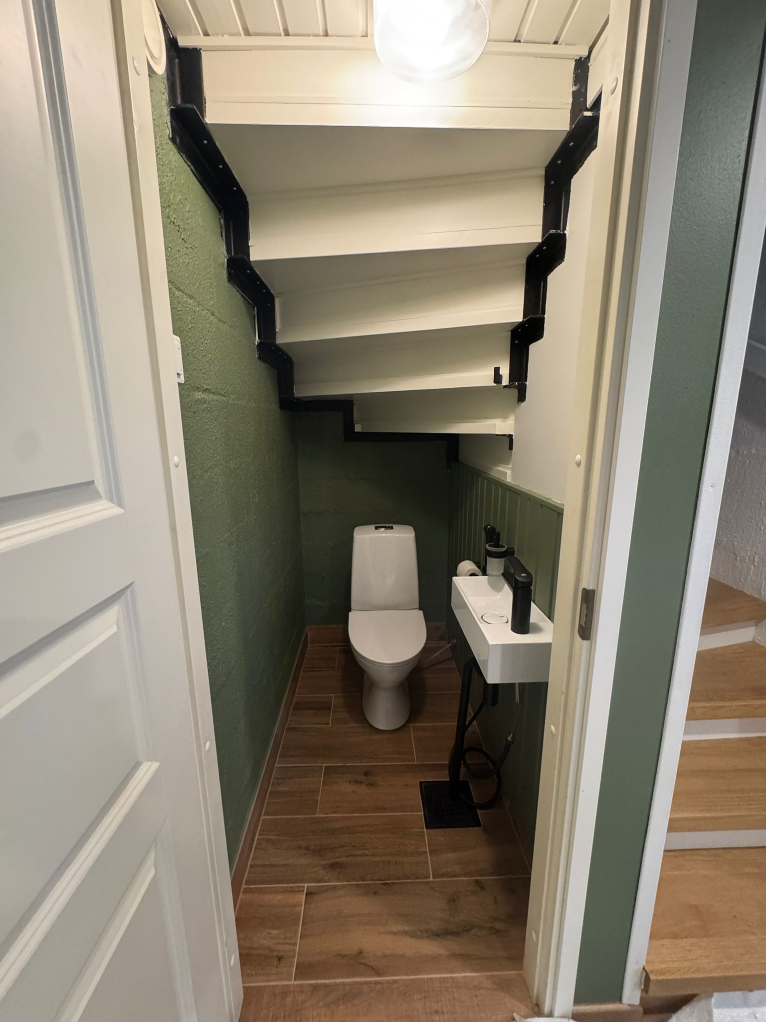 Renomen Oy huoneistoremontti Uusimaa – tyylikäs ja tilaa säästävä WC-istuin asennettuna portaikon alle.