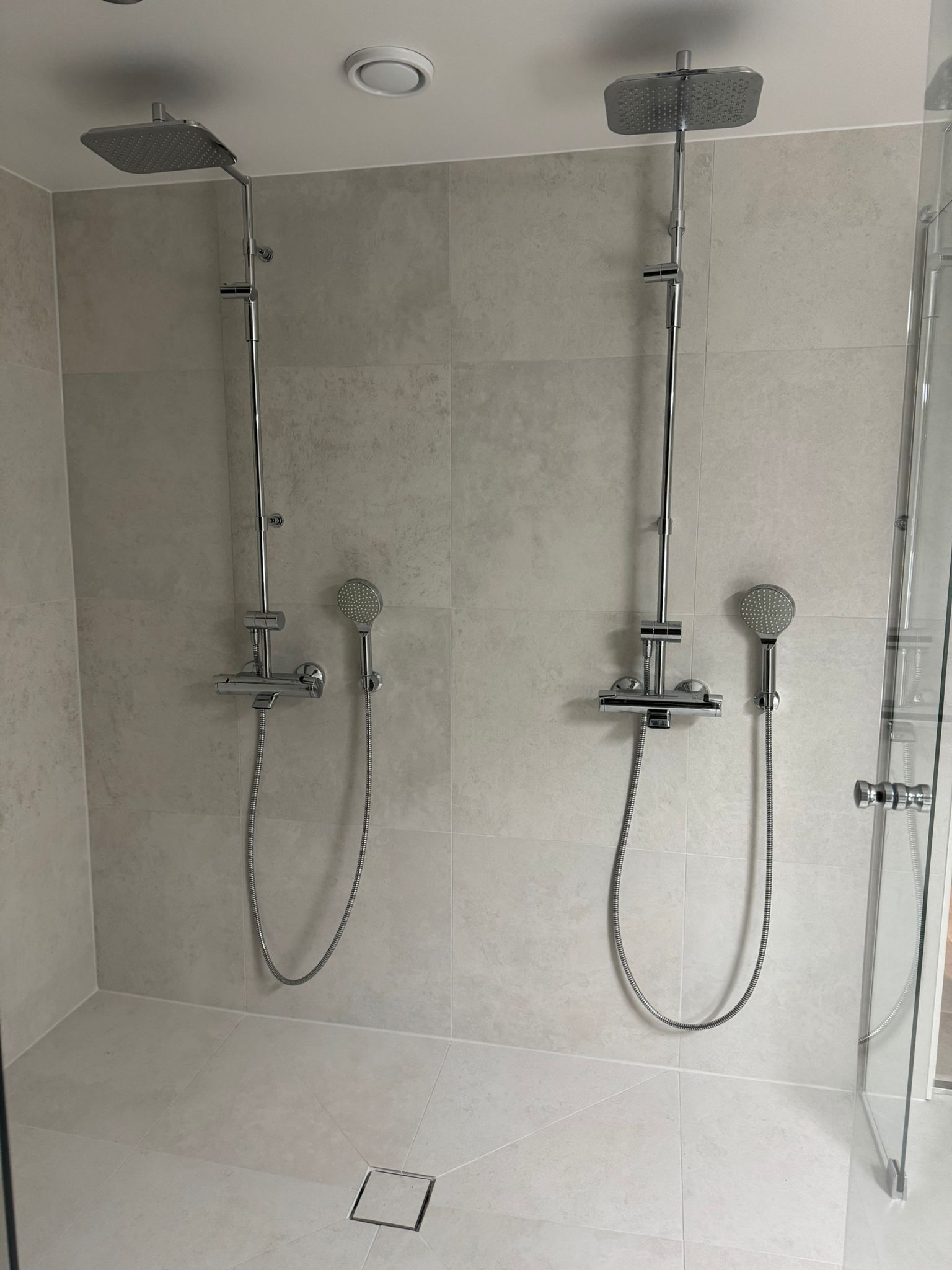 Kylpyhuoneremontti Uusimaa kaksi sadesuihkua ja suuret harmaat seinälaatat Renomen Oy.