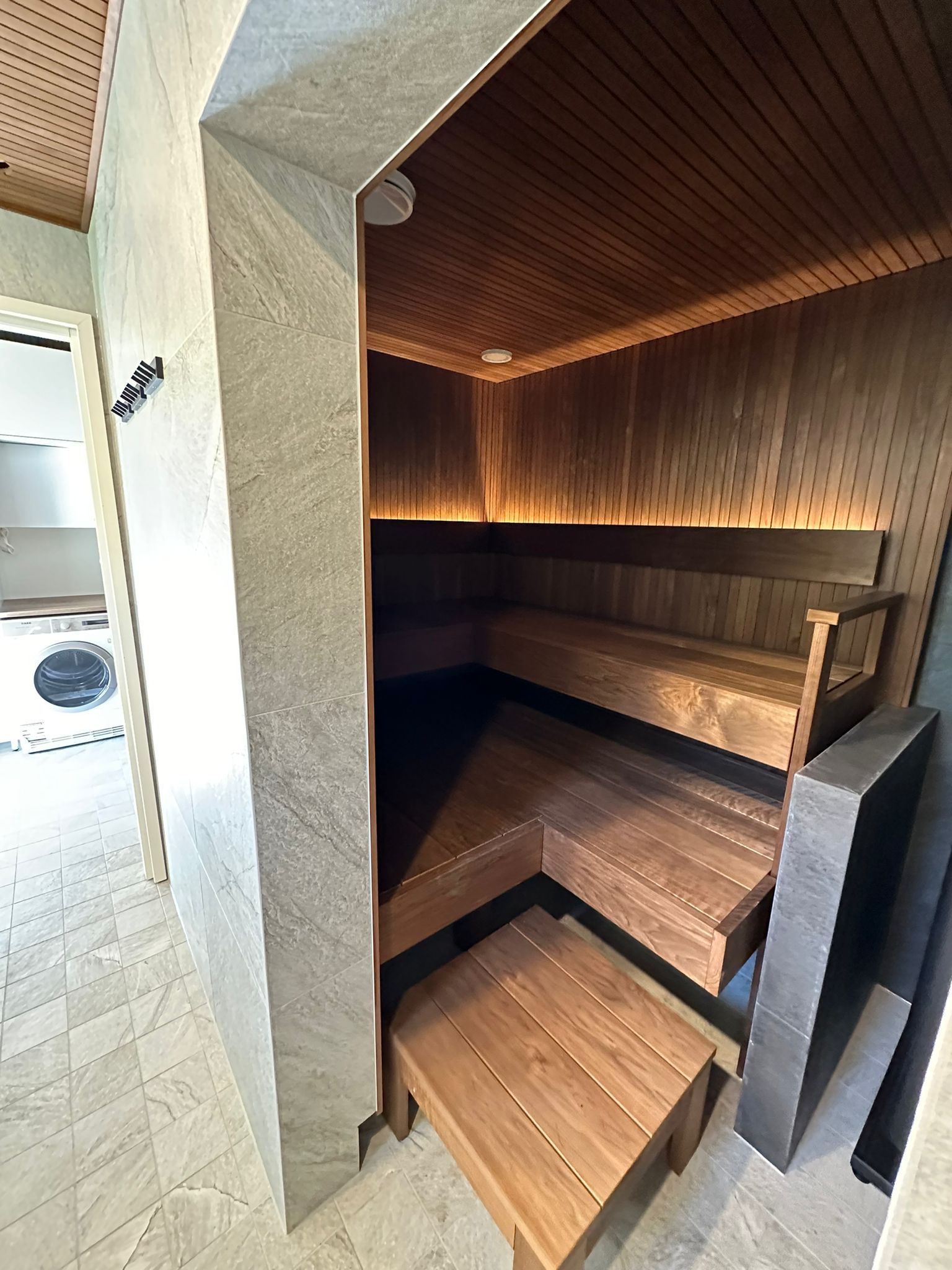 Saunaremontti ja kylpyhuone tumma paneeli lauteet ja integroitu kiuas Renomen Oy.