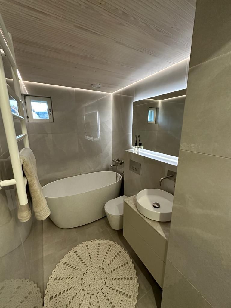 Moderni kylpyhuone vapaasti seisova amme ja epäsuora valaistus Renomen.