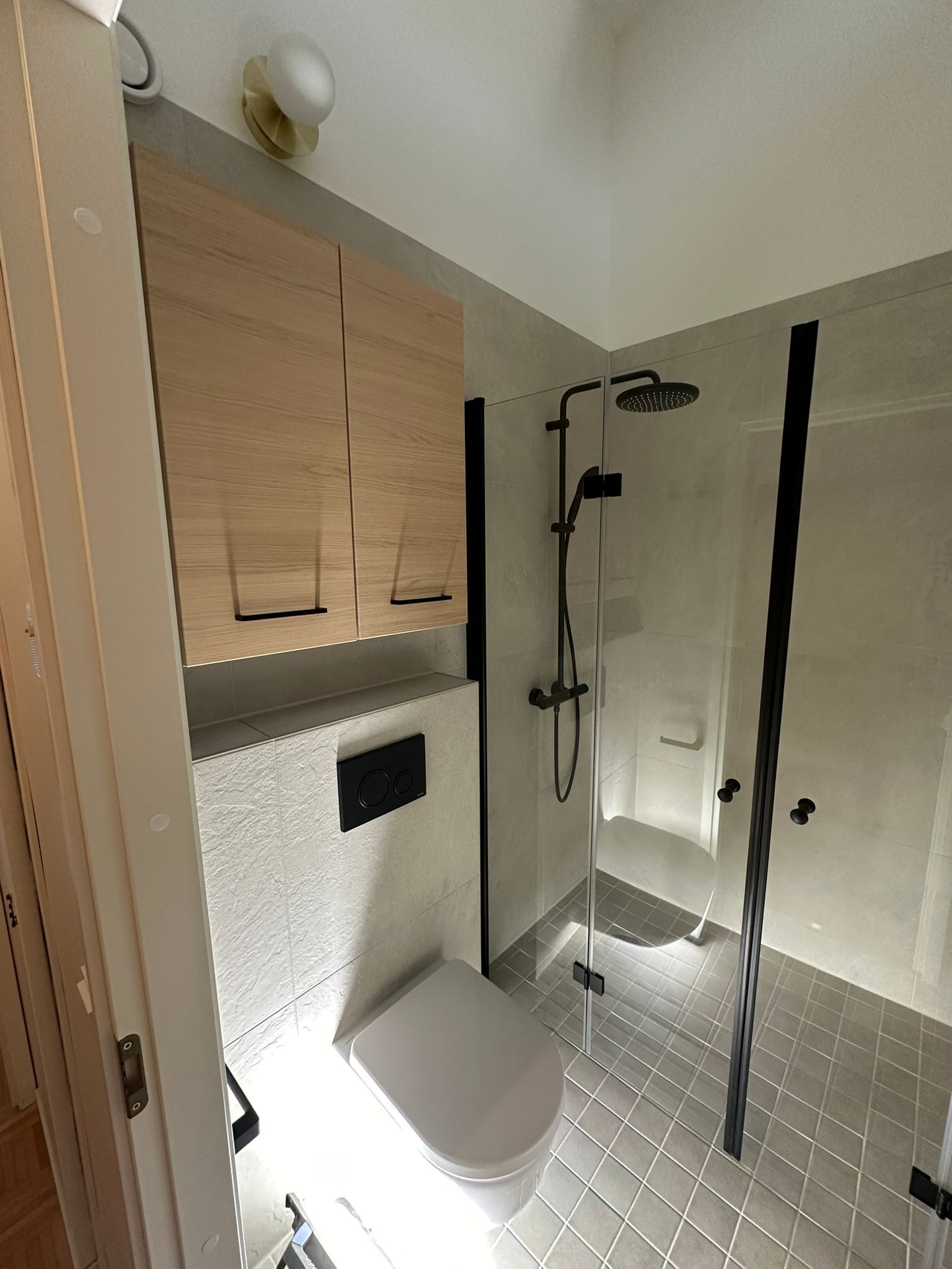 Renomen Oy kylpyhuoneremontti Uusimaa vaalea puukaappi ja musta suihku.