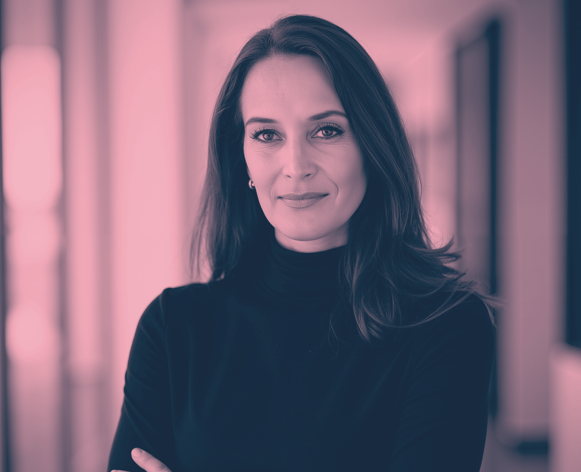 Frau mit verschränkten Armen, die einen schwarzen Rollkragenpullover trägt, lächelt.