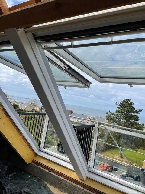 Vue urbaine depuis une fenêtre ouverte sur un paysage et des voitures dans pièce mansardée