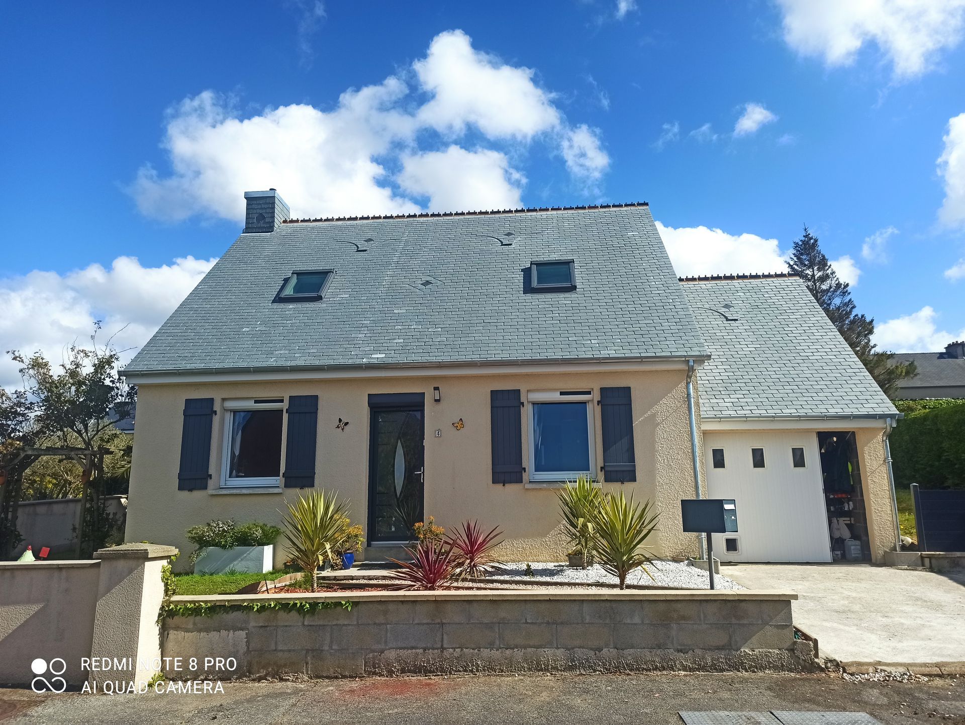 Maison en pierre au toit d'ardoise, jardin à l'avant et garage
