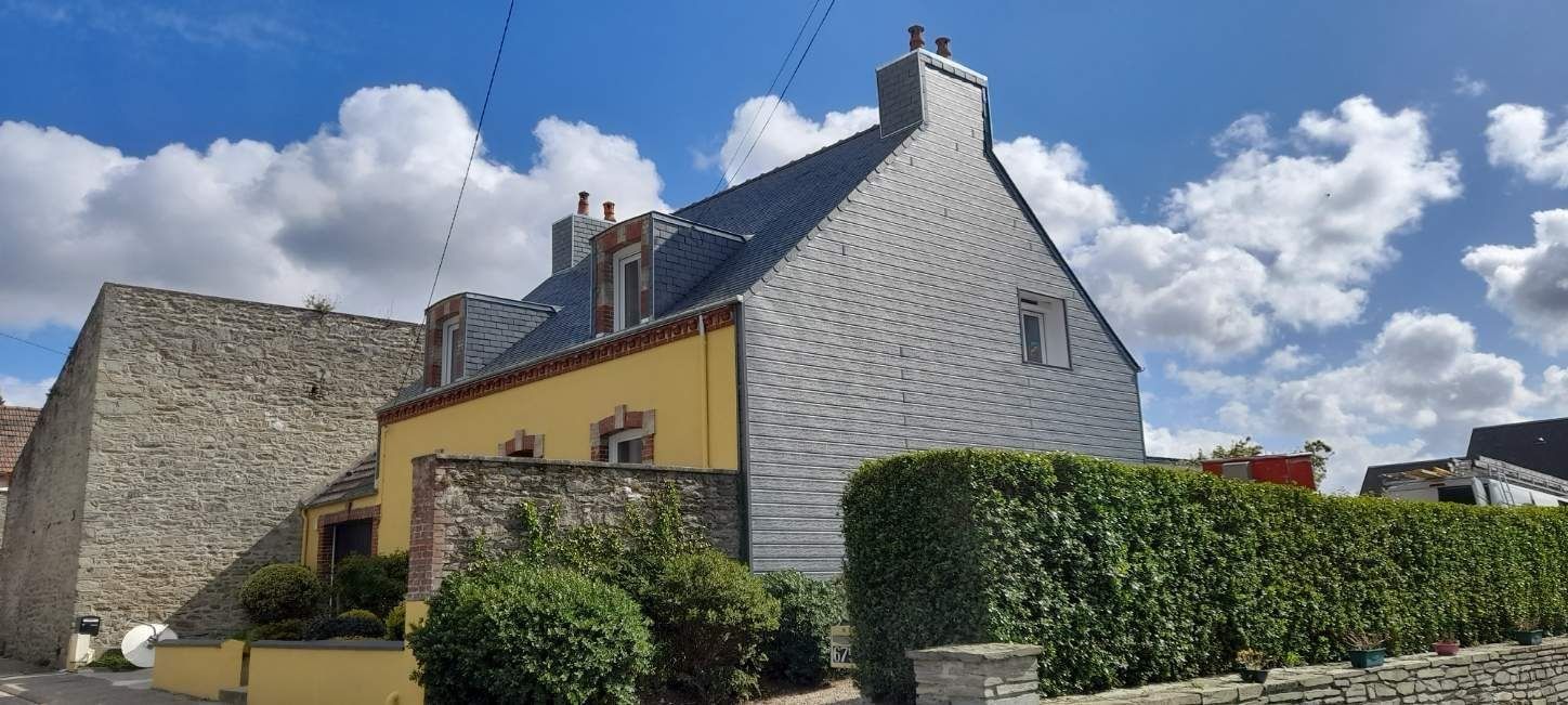 Maisons en pierre aux toits d'ardoise pentus et haies sous un ciel partiellement nuageux