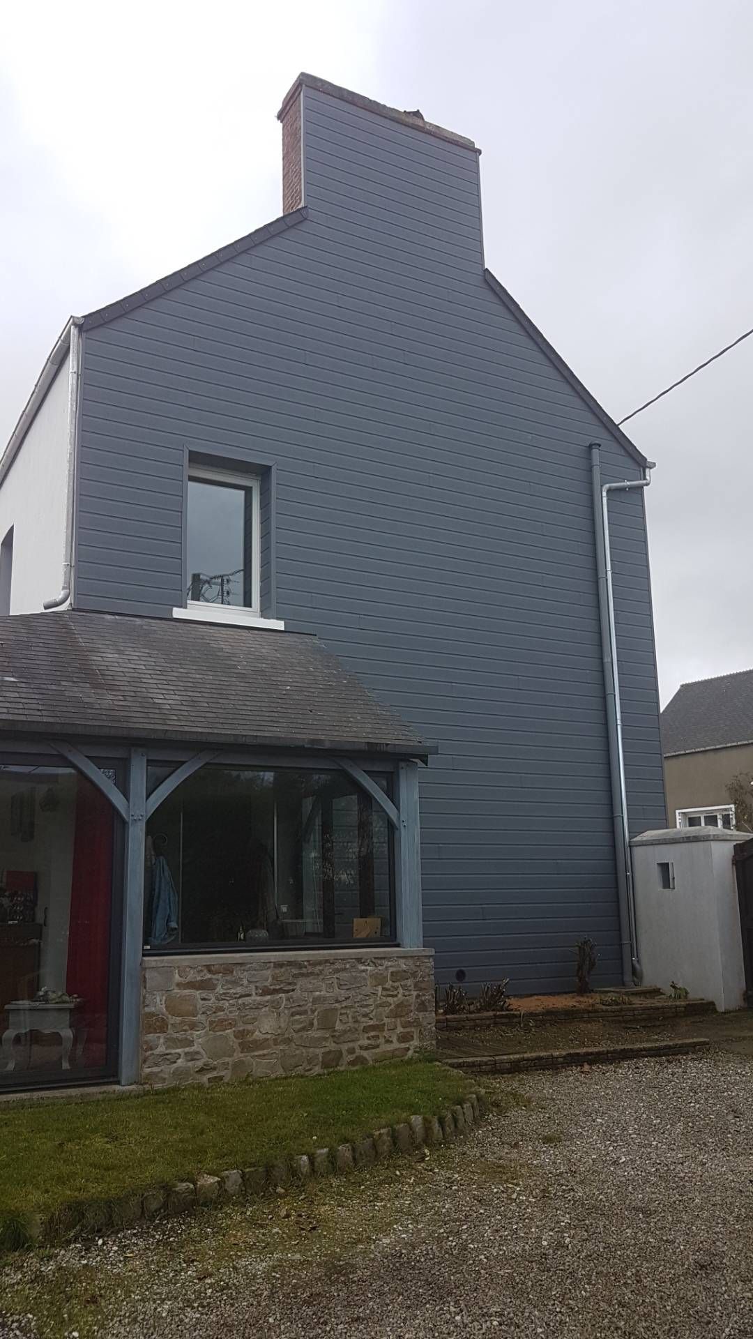 Maison à bardage gris à deux étages avec toit pentu et porche en pierre