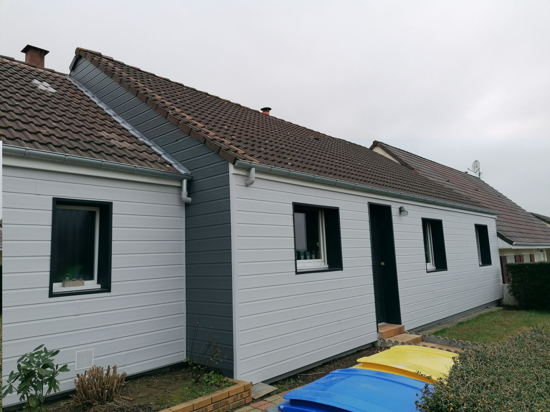 Maison à bardage blanc avec toit de tuiles donnant sur une cour