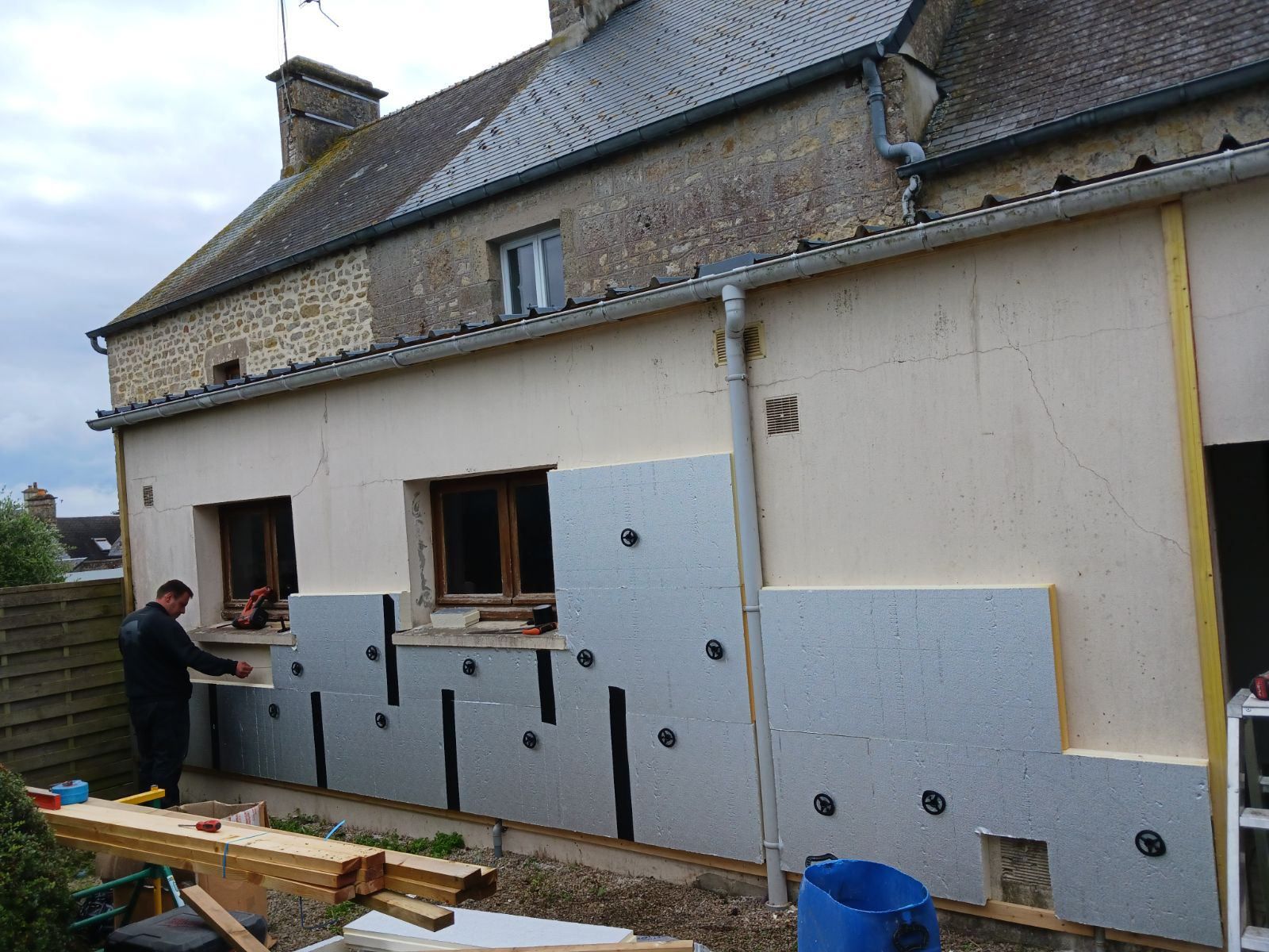Personne installant un isolant  sur un mur extérieur de maison lors de travaux de rénovation