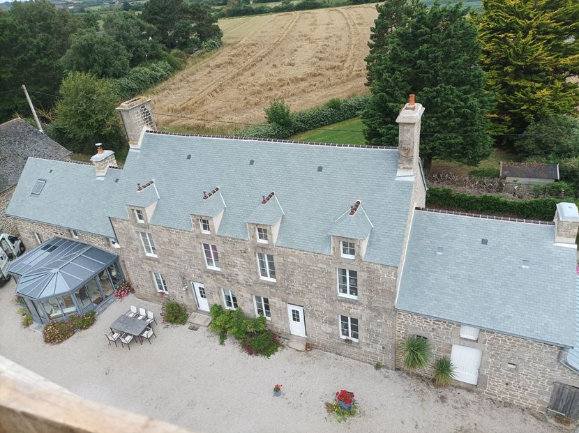 Maison de campagne en pierre avec toit gris, tables de patio 
