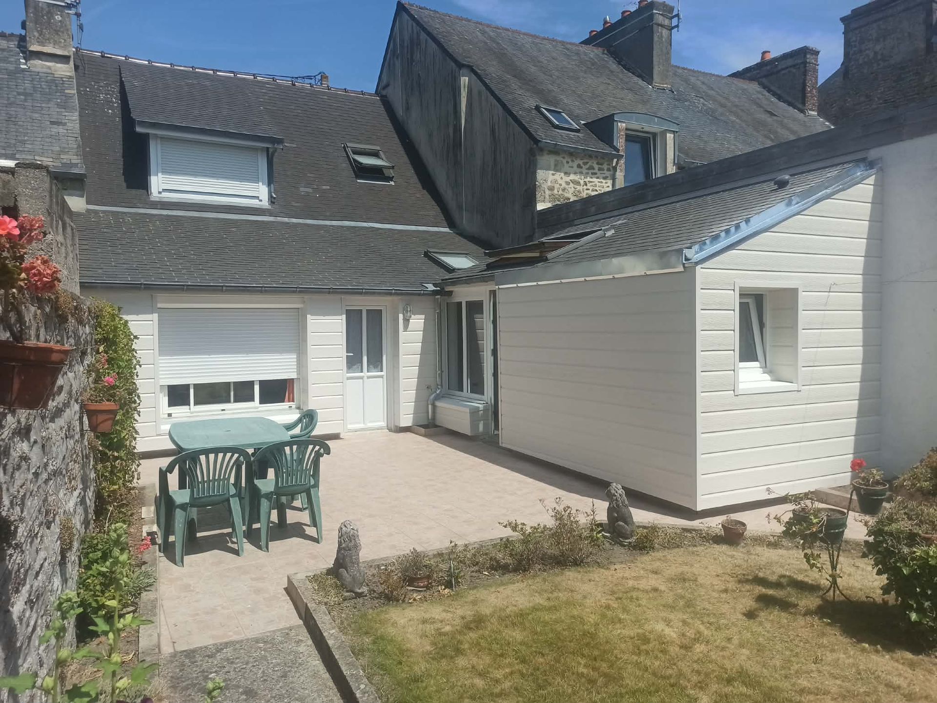 Maison à bardage blanc avec une terrasse dotée d'un salon de jardin vert