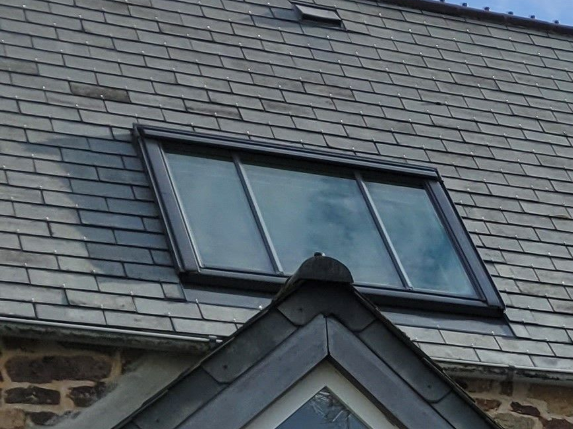 Fenêtre de toit coulissante VELUX sur un toit en ardoise