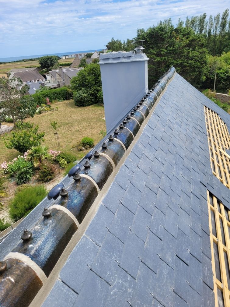 Travaux de toiture sur une maison avec des ardoises et des faîtières, vue sur la mer