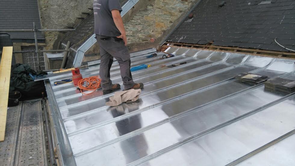 Toit en zinc naturel en cours d'installation par un ouvrier