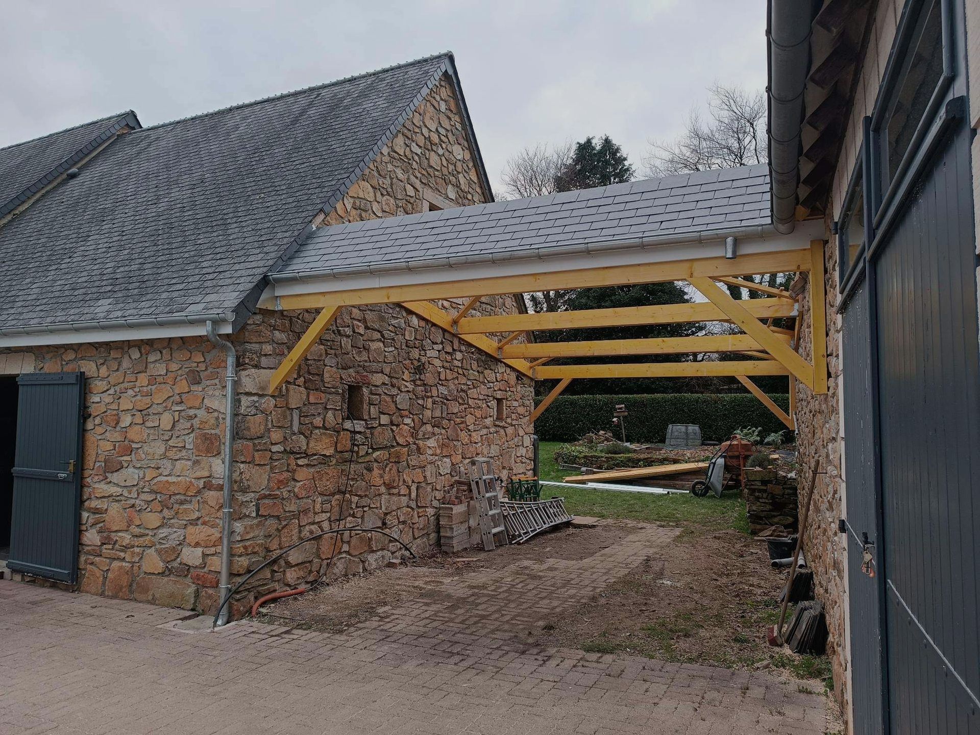 Construction en cours d'une toiture en ardoise protégeant l'espace entre deux bâtiments