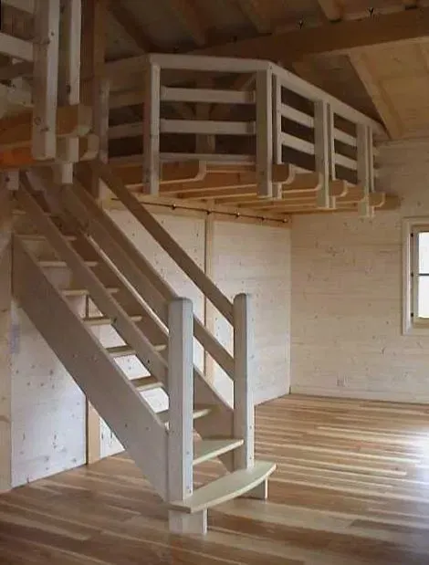 Escalier en bois avec rampe et palier menant au grenier dans une petite pièce non aménagée