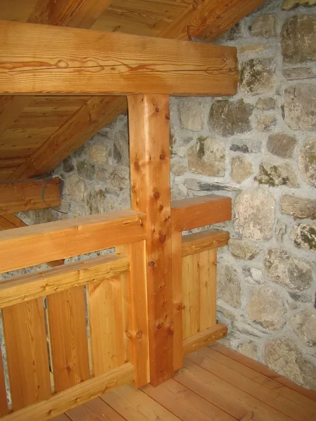 Palier d'escalier en bois avec poutres en rondins et intérieur en pierre