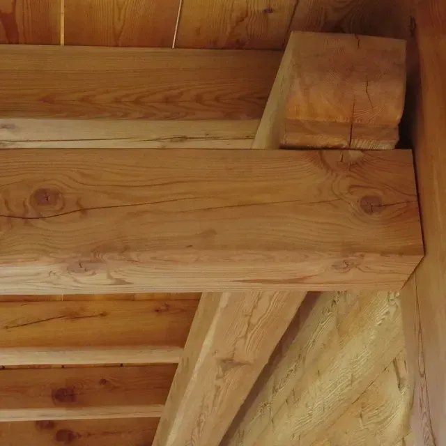 Gros plan sur des poutres et des planches de plafond en bois dans un intérieur aux tons chauds
