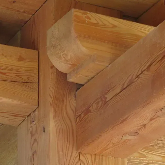 Gros plan sur des poutres en bois avec grain et assemblages visibles dans une structure à ossature bois