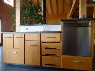 Cuisine moderne avec placards en bois, plan de travail noir et four intégré.