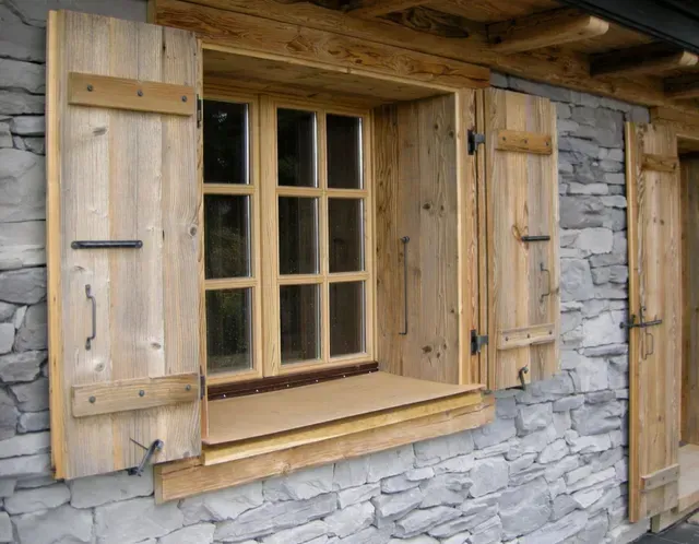 Fenêtre à volets en bois encastrée dans un mur de pierre sur l'extérieur d'une maison rustique