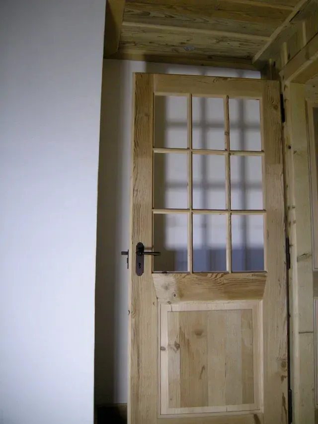Porte en bois vitrée légèrement ouverte dans un couloir rustique