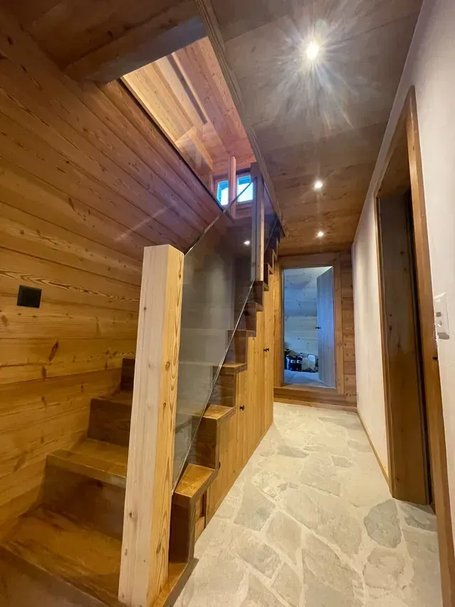 Escalier lambrissé dans un couloir étroit avec sol en pierre et puits de lumière au plafond