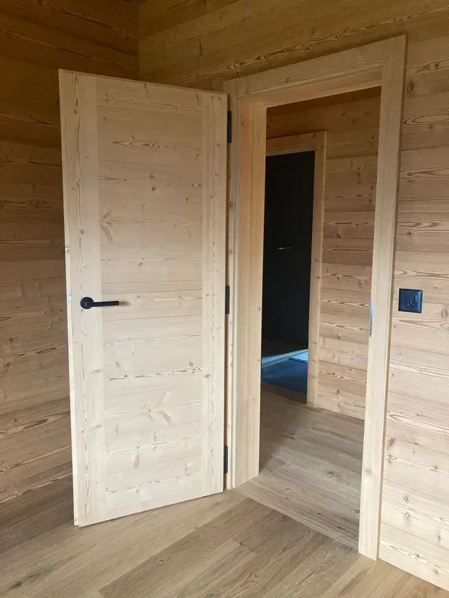 Couloir intérieur en bois avec deux portes ouvertes et parquet clair