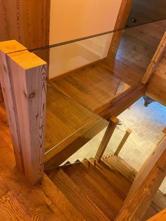 Escalier en bois avec rampe en verre et éclairage intérieur chaleureux, vu d'en haut