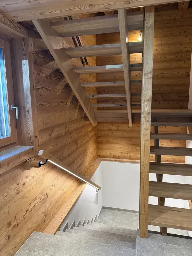 Escalier intérieur en bois avec marches ouvertes, rampes et palier vitré dans un intérieur moderne en bois