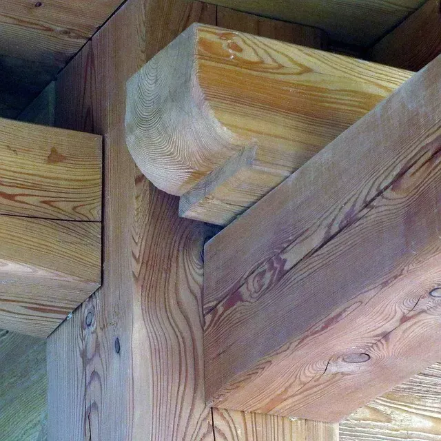 Gros plan sur les poutres et les assemblages en bois d'une charpente de plafond.