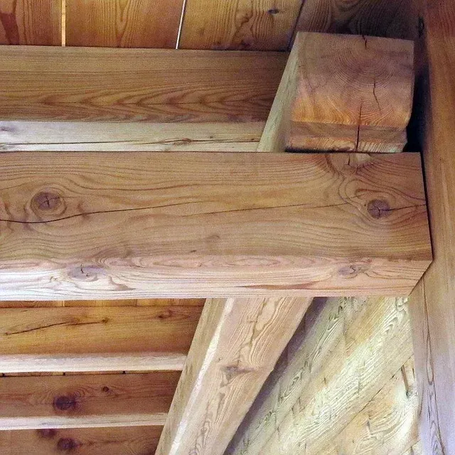 Gros plan sur les poutres et solives en bois soutenant la structure du plafond