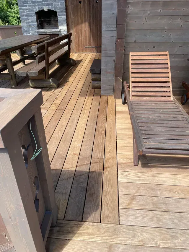 Terrasse en bois avec chaises longues, barbecue intégré et murs d'intimité en bois baignés de soleil