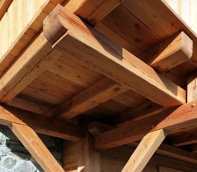 Poutres de soutien en bois sous un toit rustique, vues d'en bas.