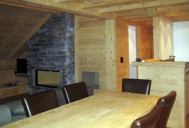 Salle à manger lambrissée avec cheminée en pierre et grande table en bois