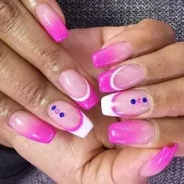 A woman 's hands with long purple nails are holding a flower.
